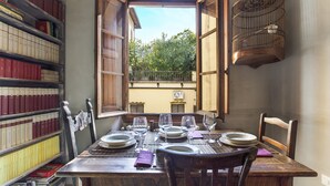 A dining table set for four with a view of a garden through an open window. - PEACEFUL OASIS IN THE HEART OF FLORENCE (FLORENCE)