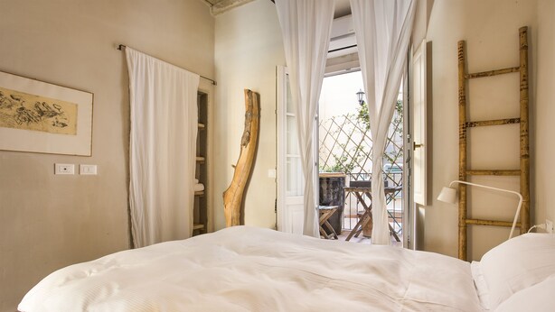 A bedroom with a large bed, white curtains, a wooden ladder, and a view of the outside balcony. - PEACEFUL OASIS IN THE HEART OF FLORENCE (FLORENCE)