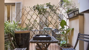 A small outdoor seating area with a wooden table and two chairs, surrounded by potted plants and a trellis. - PEACEFUL OASIS IN THE HEART OF FLORENCE (FLORENCE)