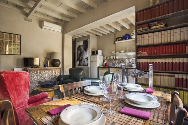 A dining area with a wooden table set for four, surrounded by bookshelves filled with books.