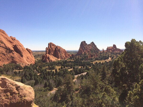 A landscape with prominent red rock formations and dense green forest. - Easy Walk to Shops, Restaurants and parks. Pet Friendly with fenced backyard. (Colorado Springs)