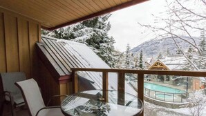Ein Zimmer mit Glastisch und -stühlen, Holzboden und Blick auf eine verschneite Landschaft mit Schwimmbecken im Freien.