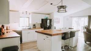 Una cocina moderna con armarios blancos, encimera de madera y una isla central con taburetes de bar.