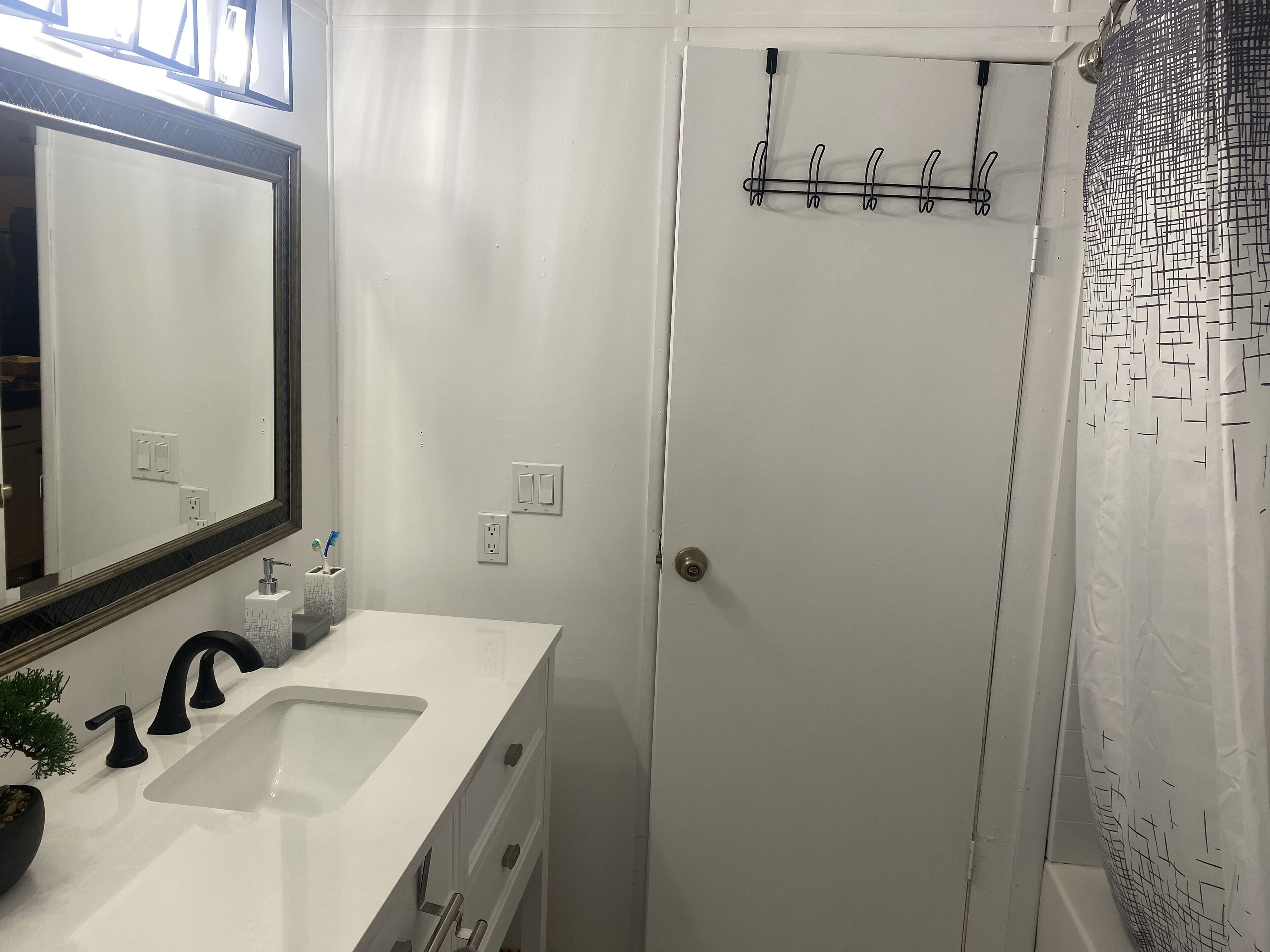 Une salle de bain avec un lavabo blanc, un miroir, un rideau de douche et un porte-serviettes.