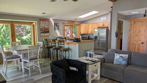 A modern kitchen with wooden cabinets, a stainless steel refrigerator, and a dining area with a table and chairs.