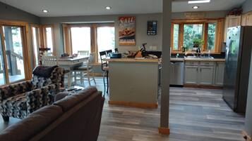 A spacious living area with a large sofa, a dining table, and a kitchen with a refrigerator and wooden cabinets.