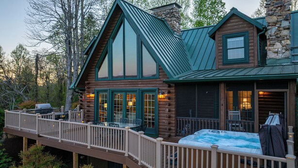 A log cabin with a deck, a hot tub, and a stone chimney. - Stunning Mountain Views on 8 Acres with Hot Tub, sleeps 10 (Saluda)