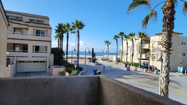 A coastal residential area with multi-story buildings, palm trees, and a view of the ocean.