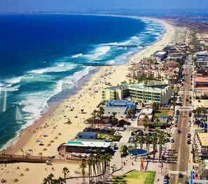 A coastal hotel with multiple buildings, a sandy beach, and a view of the ocean.