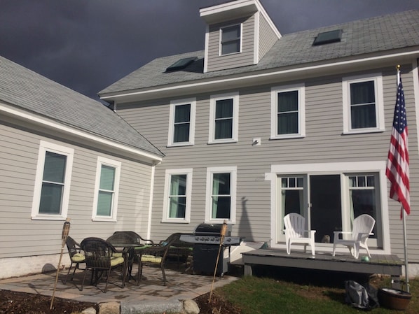 A two-story house with a patio area featuring outdoor furniture and an American flag.