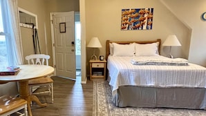 A bedroom with a bed, nightstands, a ceiling fan, a rug, and a dining area with a table and chairs.