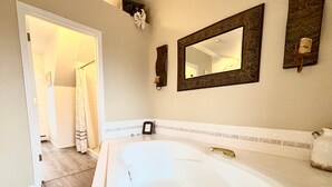 A bathroom with a large bathtub, a mirror, and a shower curtain.