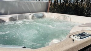 A hot tub with a control panel, surrounded by trees.