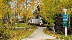 A pathway leading to a house surrounded by autumn foliage.