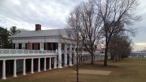 A historic building with a covered porch supported by columns, a brick facade, and a symmetrical design. - Well Appointed Home For Your Family's Enjoyment In The Heart of Charlottesville (Charlottesville)