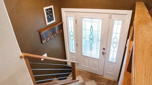 Un escalier avec une rampe en bois menant à une porte blanche ornée de panneaux de verre décoratifs.
