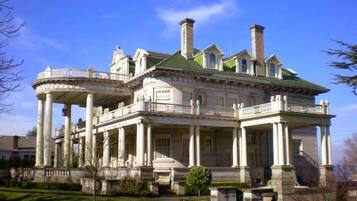 A large, historic building with classical architecture, featuring a central courtyard, multiple wings, and a prominent green roof.