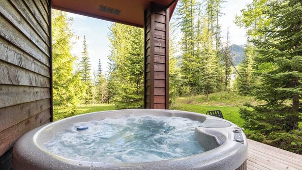 A hot tub on a wooden deck with a forest backdrop. - Ski In. 10 Minute Walk to the Lifts. Hot Tub (Fernie)