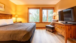 A bedroom with a bed, a desk, a television, and two windows. - Ski In. 10 Minute Walk to the Lifts. Hot Tub (Fernie)