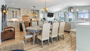A spacious kitchen with a dining area, wooden flooring, and modern lighting fixtures. - The  Kure . (Kure Beach)