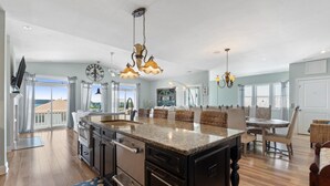 A spacious kitchen with a large island, modern appliances, and a dining area with wicker furniture. - The  Kure . (Kure Beach)