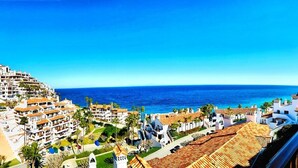 Un borgo costiero con edifici dalle tegole color terracotta, un cielo azzurro limpido e il mare sullo sfondo.