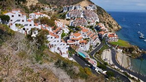 Un paese costiero con edifici bianchi, una strada curva e vista sul mare.