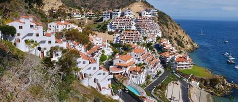 Uma vila costeira com edifícios brancos, uma estrada sinuosa e vista para o mar.