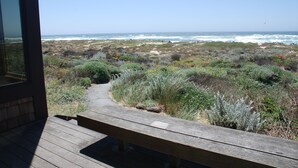 A wooden deck leading to a beach with a clear view of the ocean.