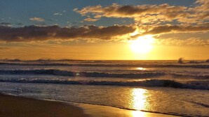 A beach with waves and a sunset.