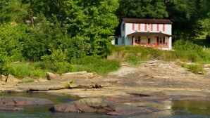 Una casa lungo un fiume con un molo di legno.