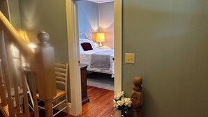 Una scala conduce a una camera da letto con un letto, un comodino, una lampada e una finestra con vista.