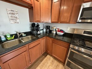 A kitchen with wooden cabinets, a double sink, a microwave, and a stove.