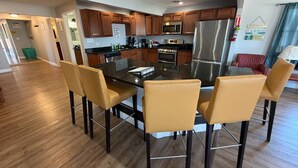 A modern kitchen with wooden cabinets, stainless steel appliances, and a central island with chairs.