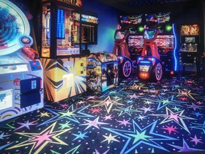 A room with arcade machines, a neon sign, and a star-patterned floor.