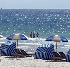 A beach with striped umbrellas and lounge chairs.