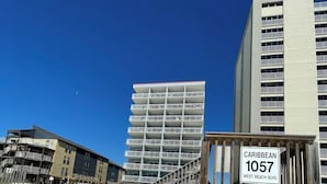 Eine Holztreppe führt zu einem Strandbereich, mit einem Schild mit der Aufschrift Caribbean 1057 West Beach Blvd.