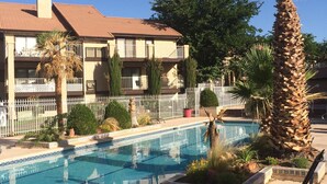 A pool area with a clear blue pool, surrounded by palm trees and a building with balconies. - Don't Click Here UNLESS You Want The Best Value In Southern Utah! (St George)
