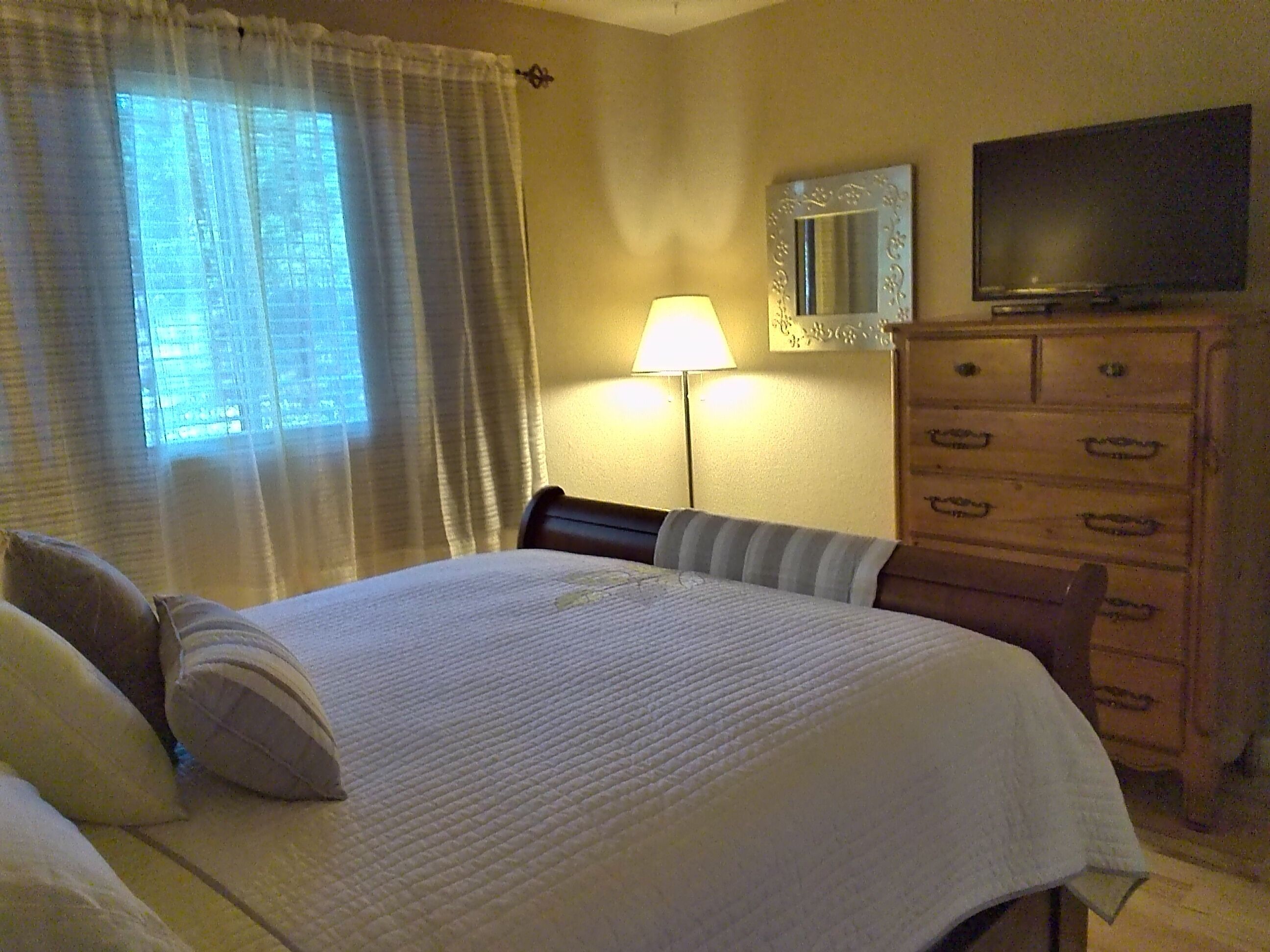 Een hotelkamer met een bed, een dressoir, een televisie en een lamp.