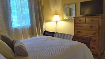 Een hotelkamer met een bed, een dressoir, een televisie en een lamp.