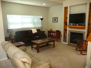 A living room with a sofa, coffee table, TV, fireplace, and bookshelves.