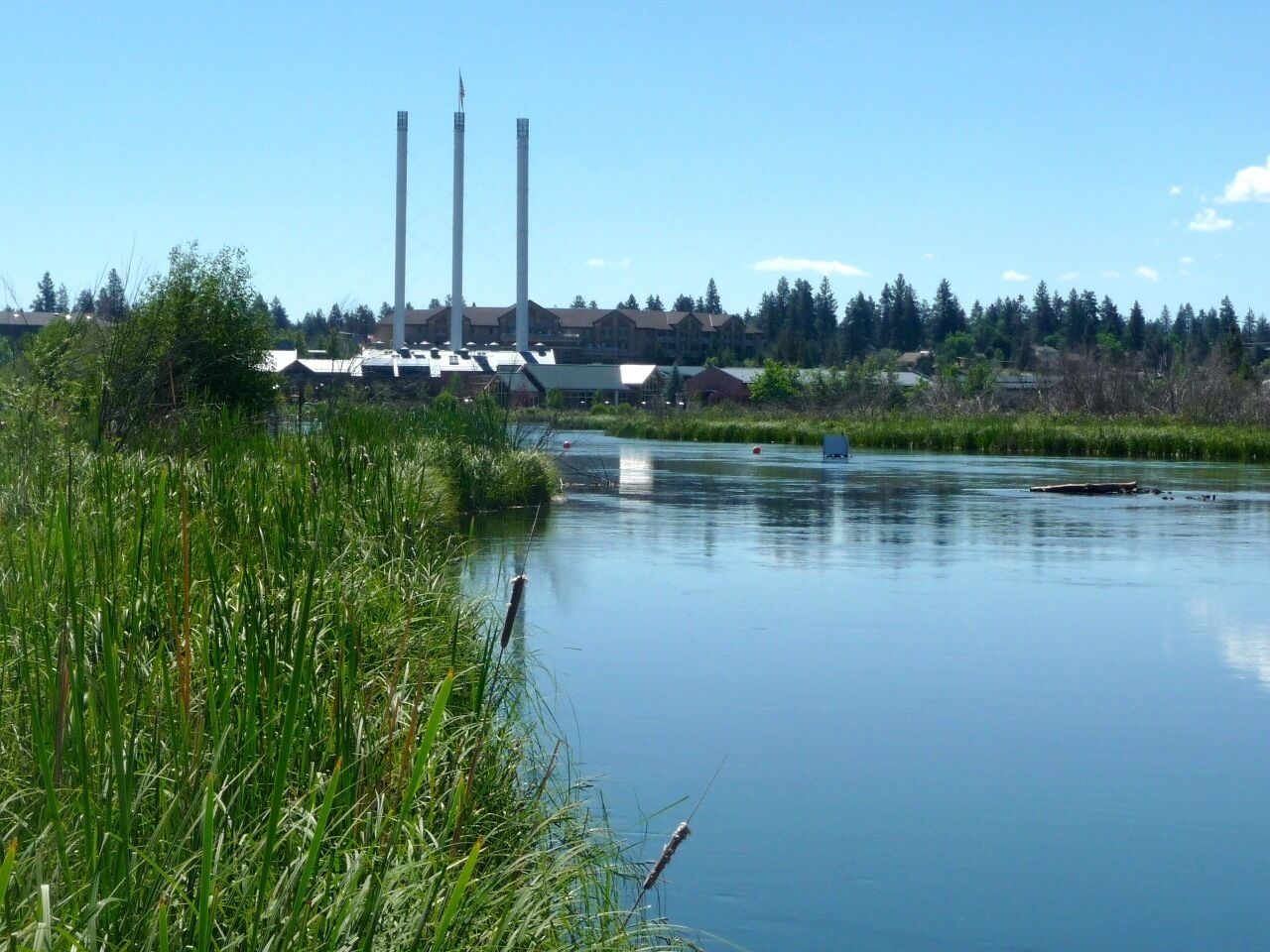 A calm river with industrial buildings in the background.