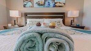 A neatly made bed with rolled towels and three chocolate-covered desserts on top. - Beachfront luxury loft - overlooking Babe's beach Dawn-Bldg 10 (Galveston)