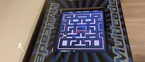 A retro video game console with a maze game displayed, a chair, and a wooden floor.