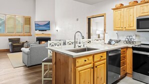 Una cocina moderna con armarios de madera, estufa integrada y una isla grande con pileta.