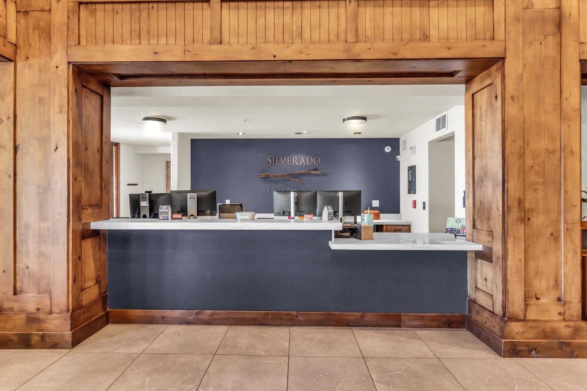 A reception desk with a dark blue backdrop, wooden paneling on the walls, and a sign that reads 'SILVERADO'.