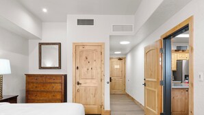 Habitación de hotel con cama, armario de madera y pasillo que conduce a una zona de cocina.