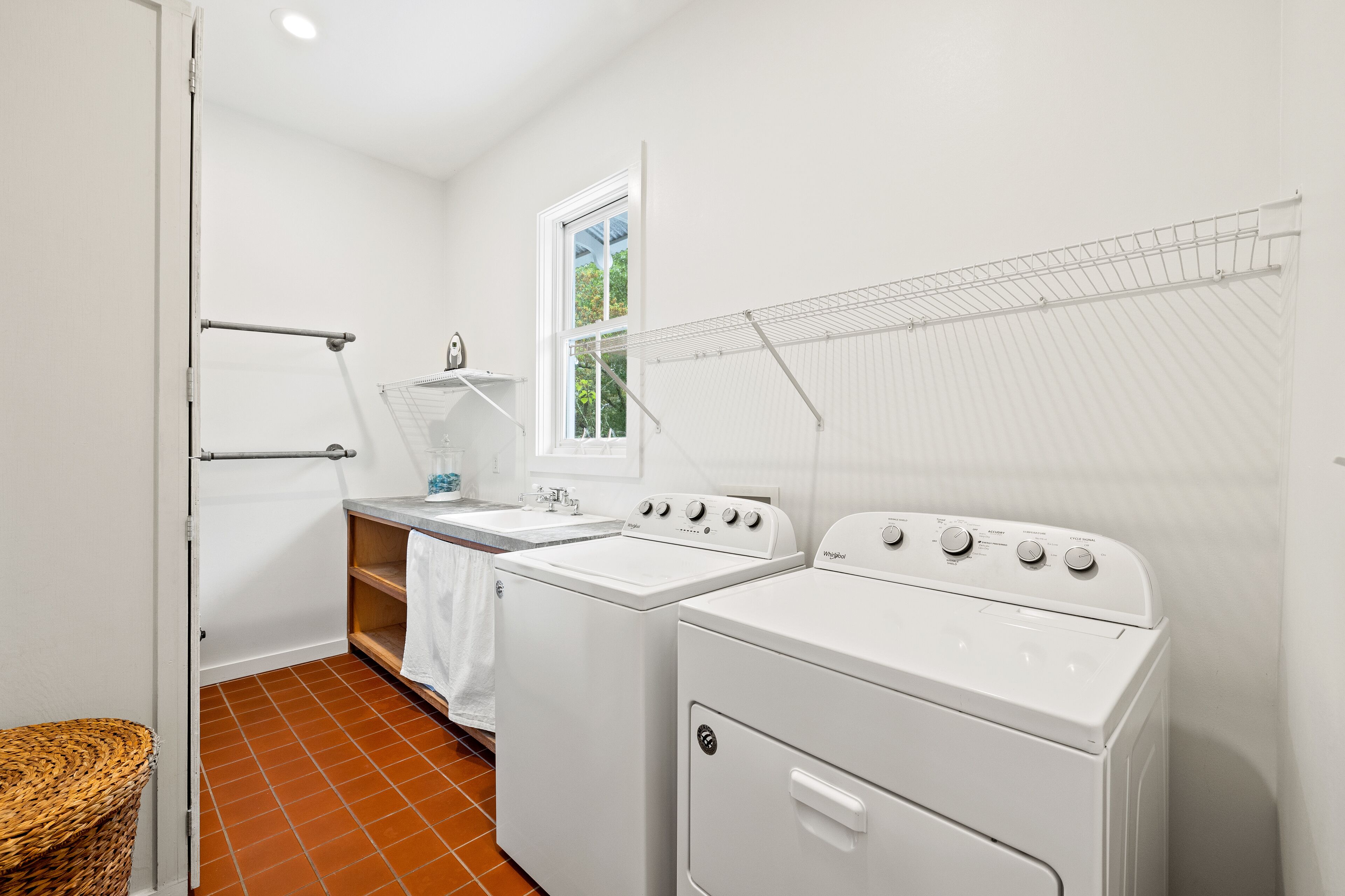 A laundry room with a washing machine, dryer, and a drying rack.