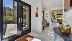 Un interior moderno con puerta de vidrio de entrada, zona de cocina y comedor.