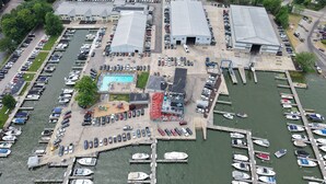 An aerial view of a marina with boats docked, a swimming pool, and several large buildings. - The Staterooms 2J, Directions, Newly Built, Seasonally Heated Pool, Beach Nearby (Holland)